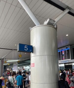 Blue display sign'5 2F' attached to a large gray pillar in a busy train station concourse.