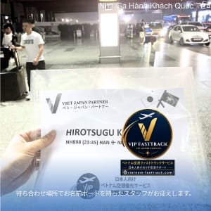 Close up of a hand holding a VIP FASTTRACK badge at an airport arrivals area featuring a blue circular VIP FASTTRACK emblem and partner text in the background